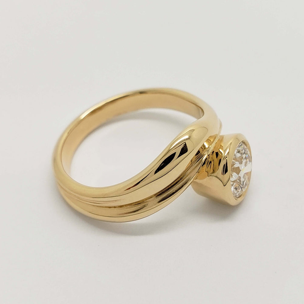 Side profile of 14kt yellow gold curvy ring with bezel-set round lab diamond