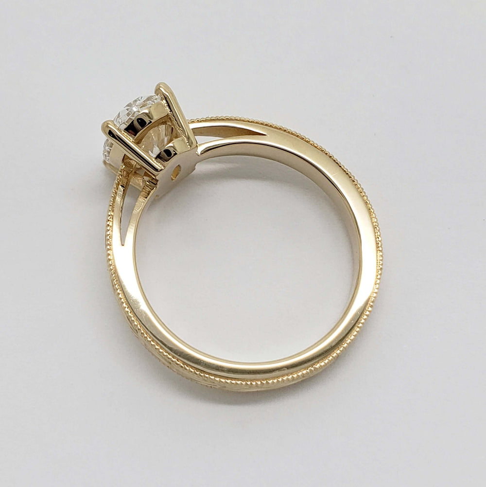 Side profile of 14kt yellow gold engagement ring with oval lab diamond and millgrain edge