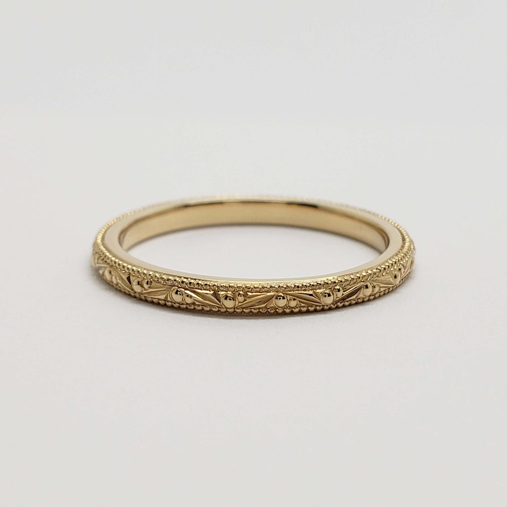 Side view of engraved 14kt yellow gold wedding band with millgrain detail