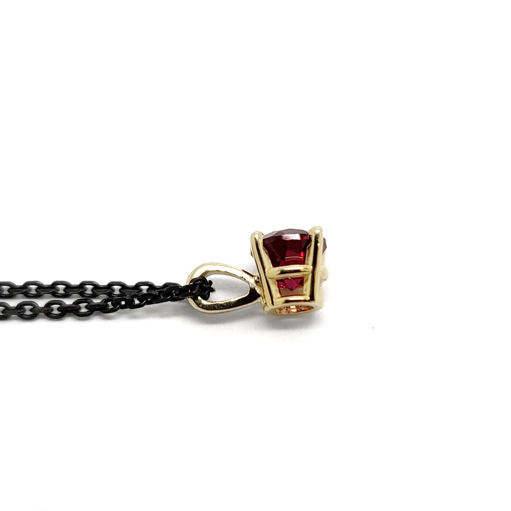 Side view of 14kt yellow gold pendant with round lab ruby and black chain