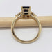 Side profile of 14kt yellow gold ring with blue sapphire and lab diamonds, resting on a pencil