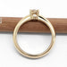 Side profile of 14kt yellow gold solitaire engagement ring with diamond, on wood
