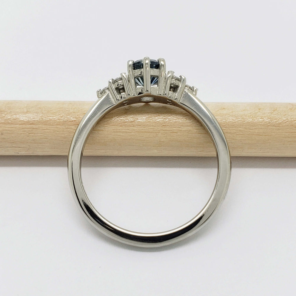 Side view of 14k white gold ring with Montana sapphire and diamonds on a pencil
