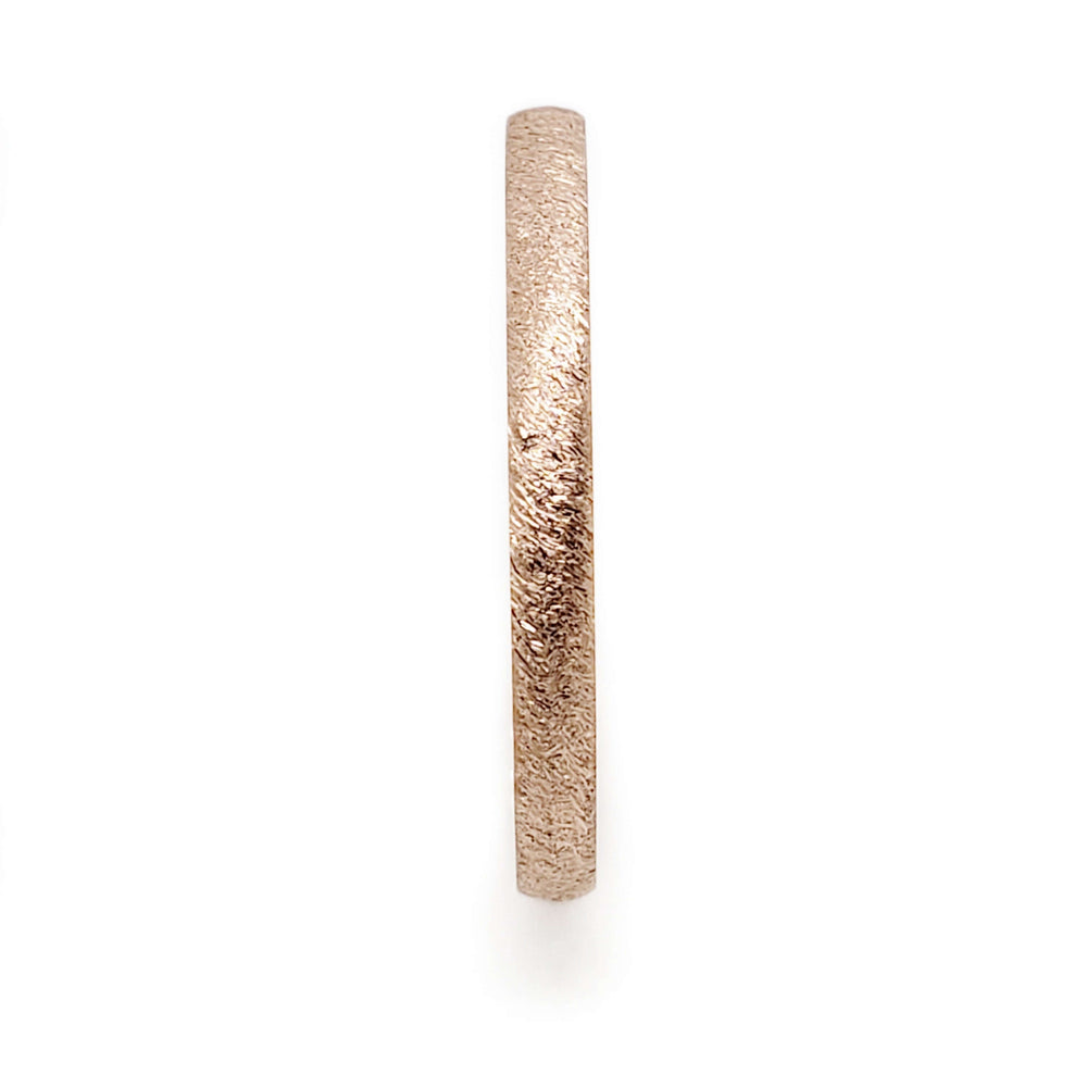 Side profile of a 14kt rose gold wedding ring with saw blade texture