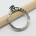 Side view of engraved white gold ring with blue Montana sapphire and diamond accents on a pencil