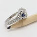 Side view of engraved white gold ring with blue sapphire accent and lab diamond, next to a pencil