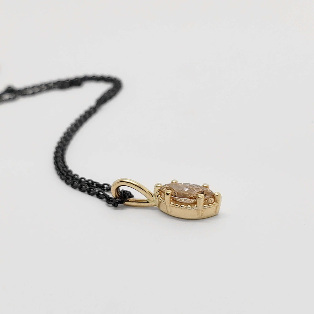 Side view of marquise champagne diamond pendant in 14kt yellow gold with beaded halo