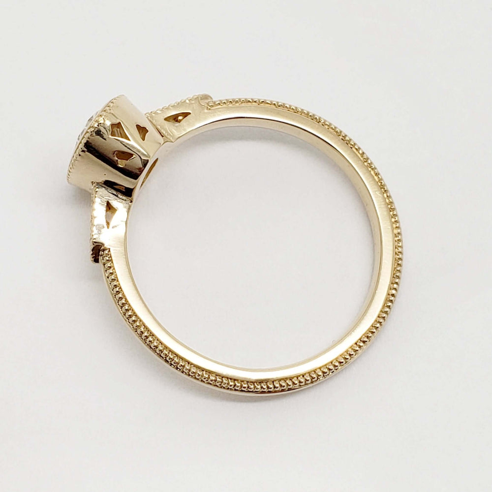 Side profile of milgrain-detailed yellow gold engagement ring showing openwork setting