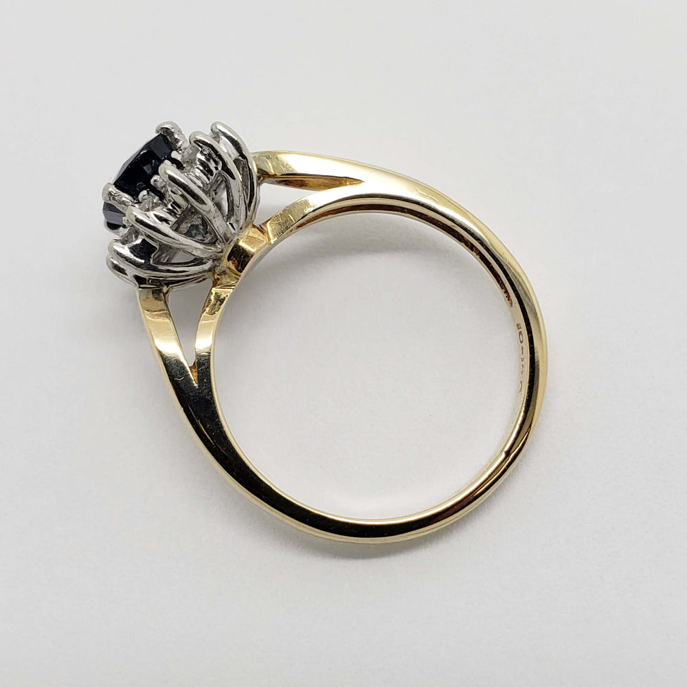 Side profile of sapphire and diamond halo ring showing two-tone gold setting