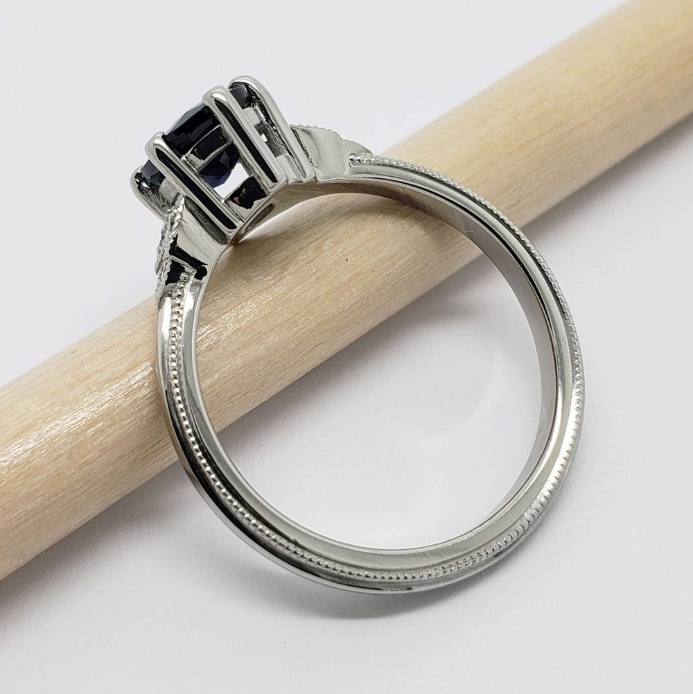 Side view of white gold ring with blue sapphire and diamond accents, millgrain edge