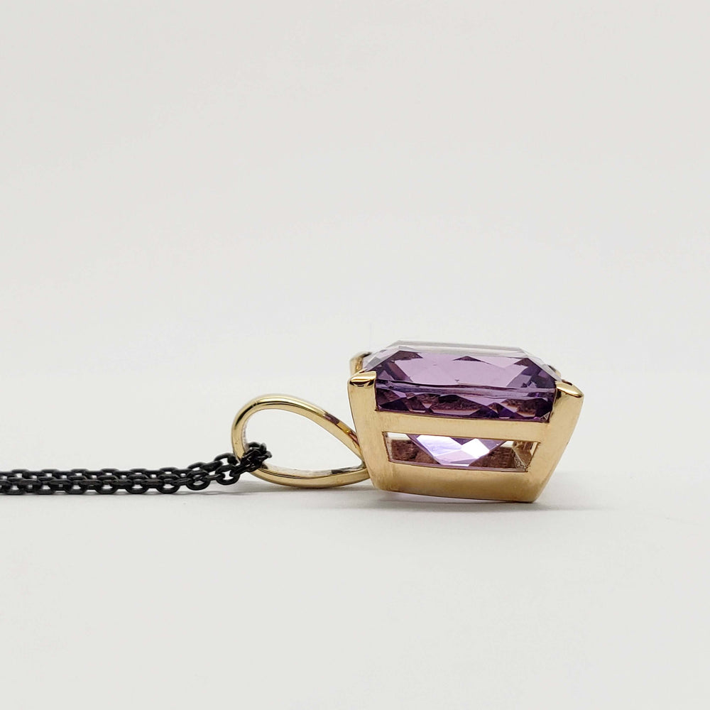 Side view of 14kt yellow gold pendant with barrel-cut purple amethyst and black chain
