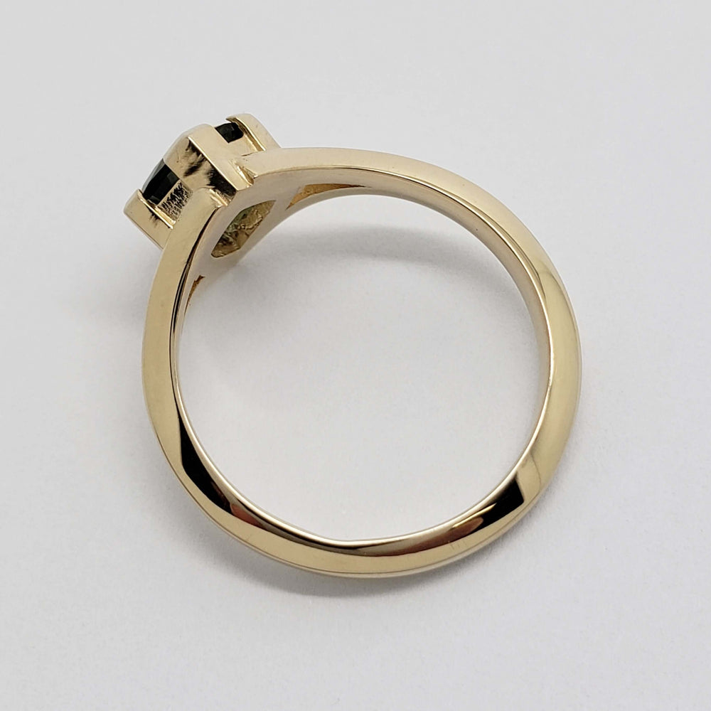 Side profile of yellow gold engagement ring with teal sapphire, showing band and setting