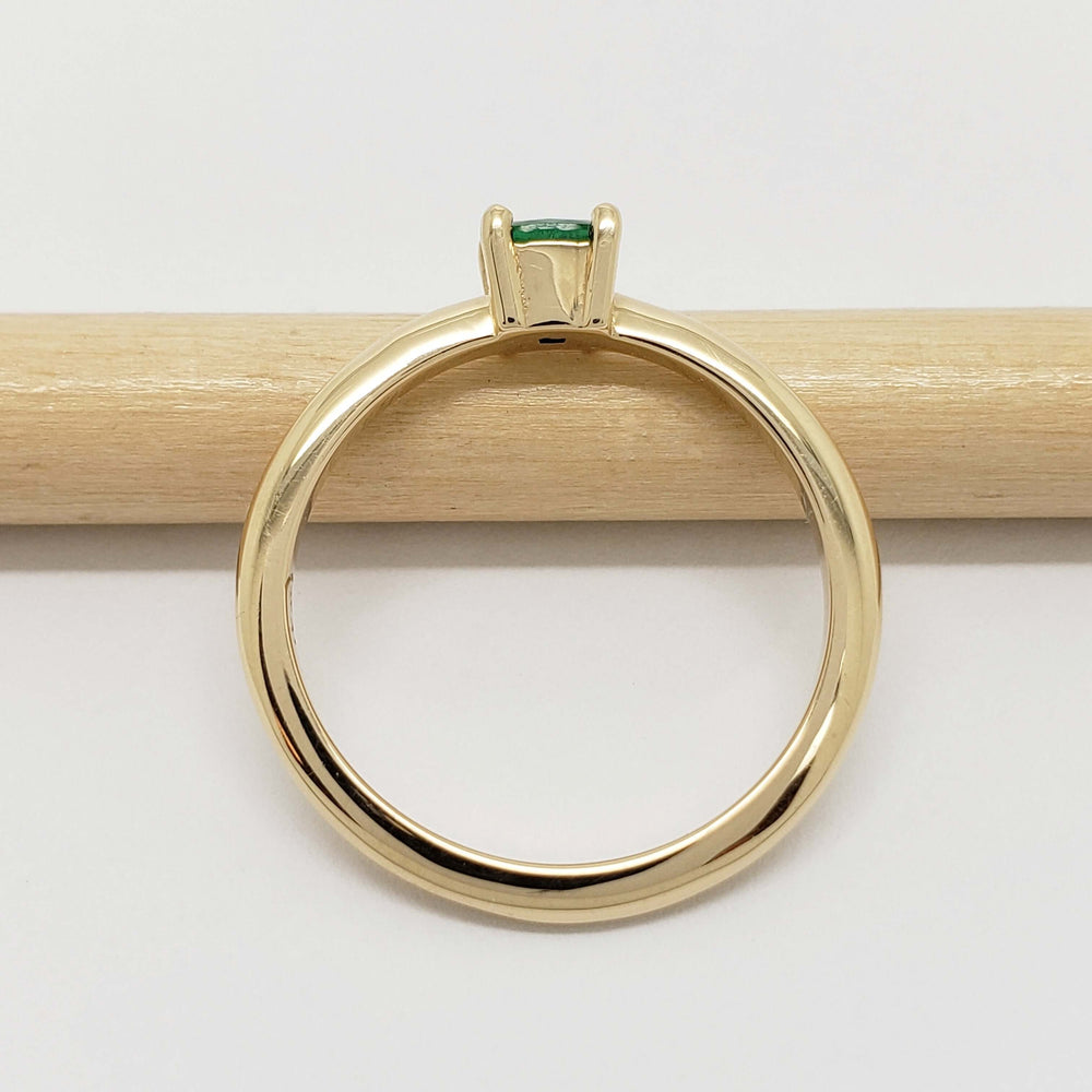 Side view of 14kt yellow gold ring with cushion emerald on a pencil