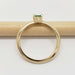 Side view of 14kt yellow gold ring with cushion emerald on a pencil