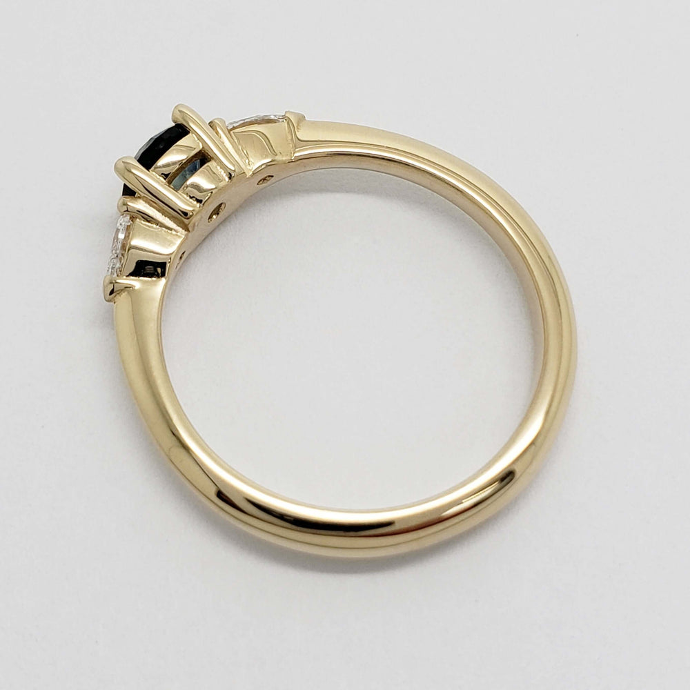 Side view of yellow gold band and three-stone sapphire and diamond setting