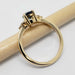 Side view of 14k yellow gold ring with blue sapphire and diamond accents, on a pencil