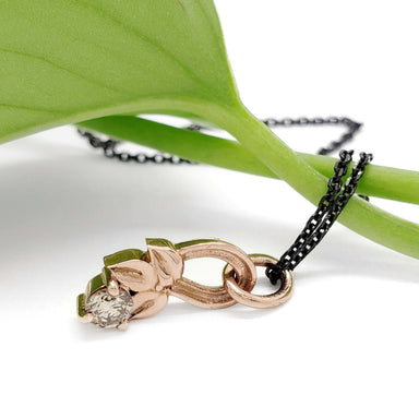 Side view of 14kt rose gold leafy pendant with champagne diamond and black chain