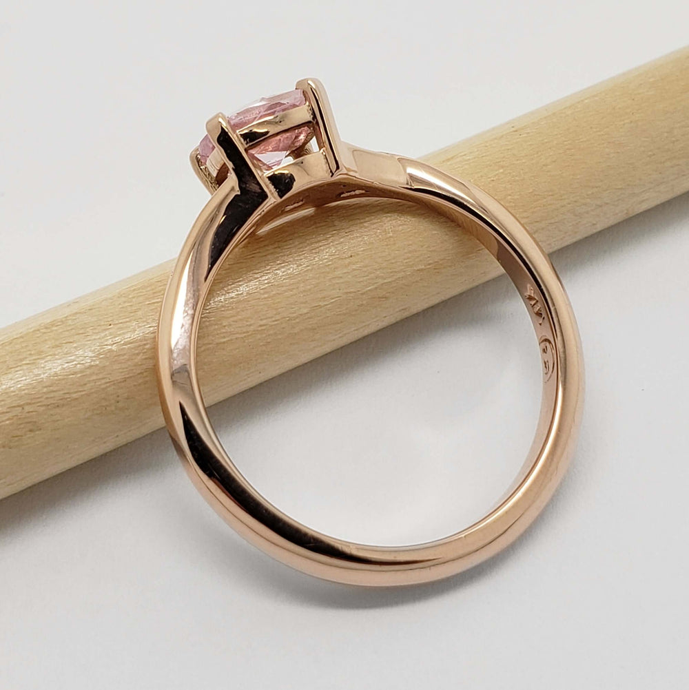 Side view of 14kt rose gold ring with pink sapphire in four-claw setting