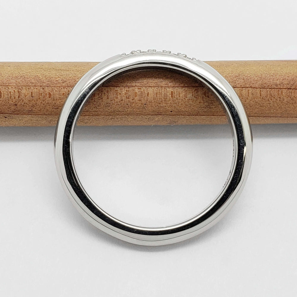 Side view of 14kt white gold chevron wedding ring on a pencil