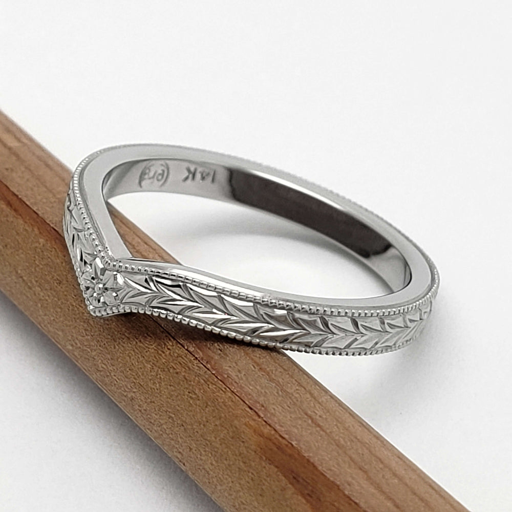 Side view of 14kt white gold chevron wedding ring with hand engraving and millgrain edge