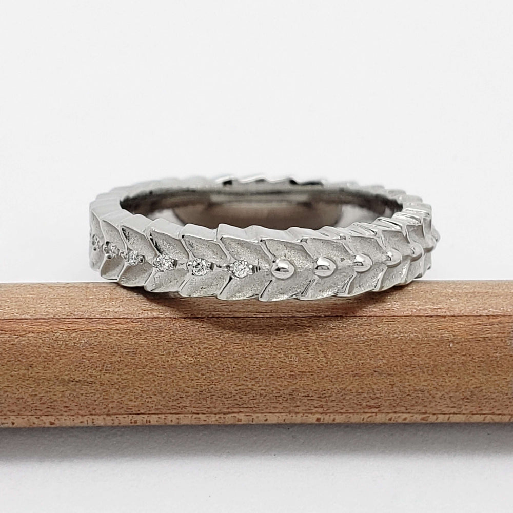 Side view of 14kt white gold leafy diamond wedding ring, resting on pencil