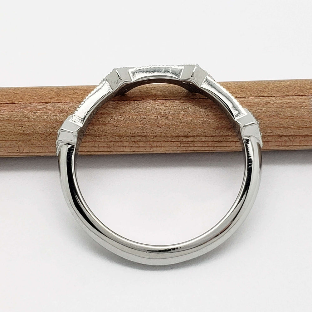 Profile view of 14kt white gold wedding band with millgrain detail on a pencil