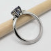 Side view of 14kt white gold ring with blue-grey spinel and triangle diamonds on a pencil