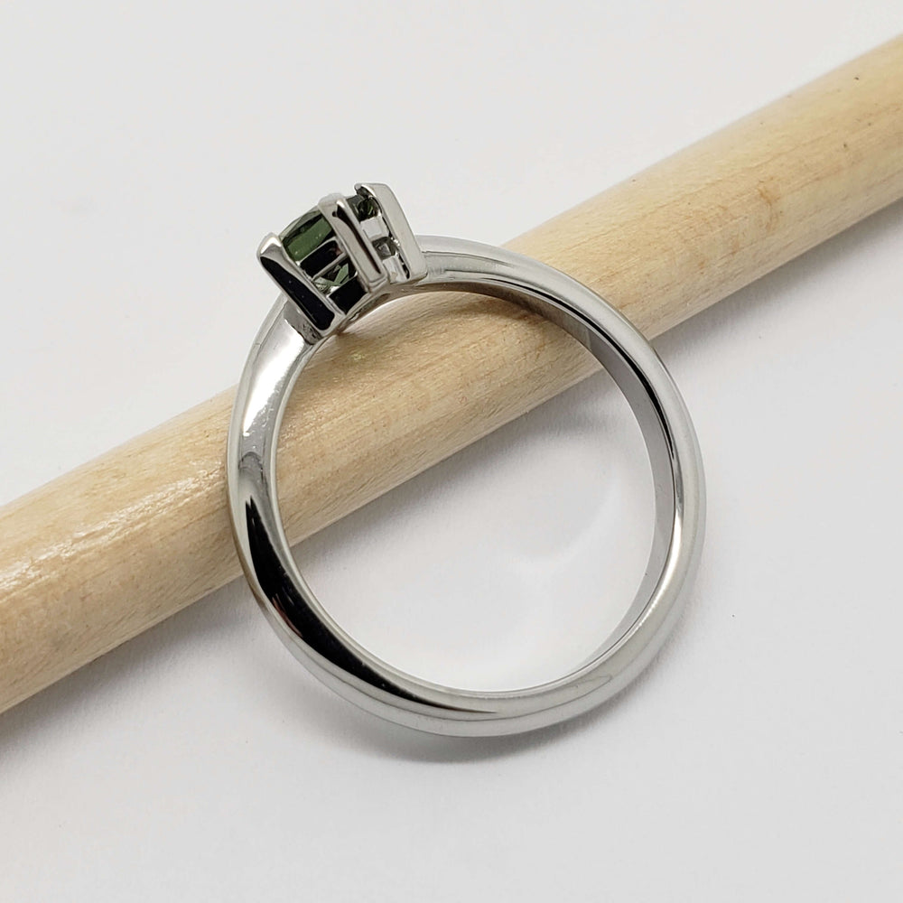 Side view of 14kt white gold ring with green sapphire on a pencil