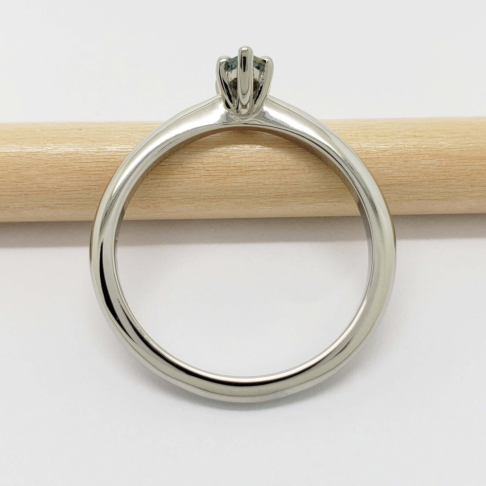 Side view of 14kt white gold ring with marquise Montana sapphire on a wooden stick