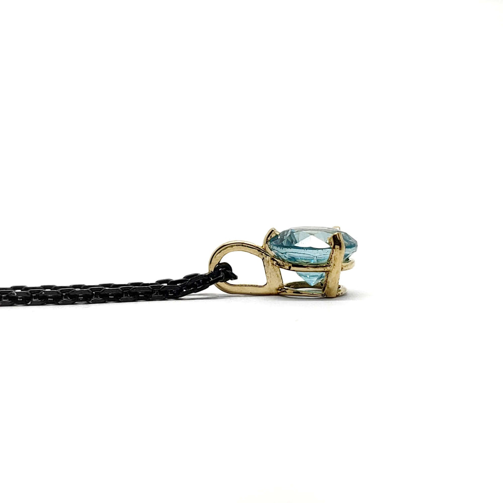 Side profile of 14kt yellow gold pendant with round blue zircon on black chain