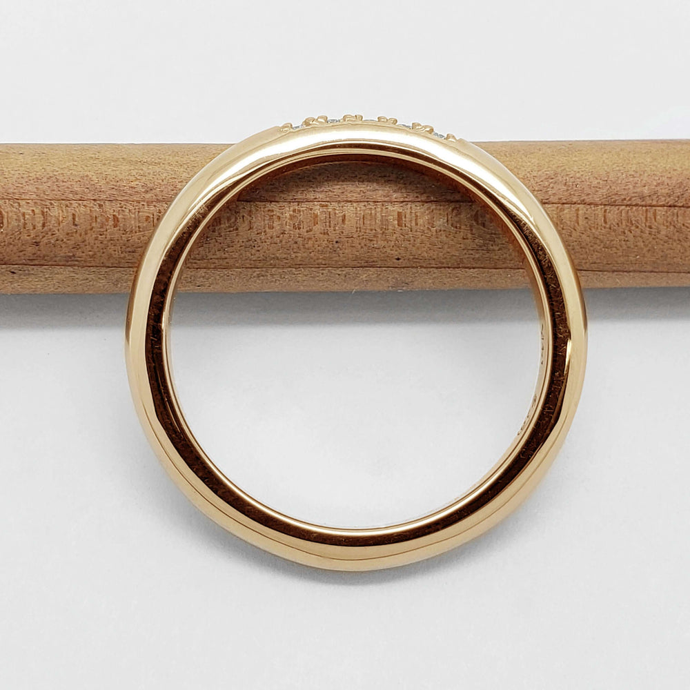 Side view of 14kt yellow gold chevron wedding ring on a wooden stick