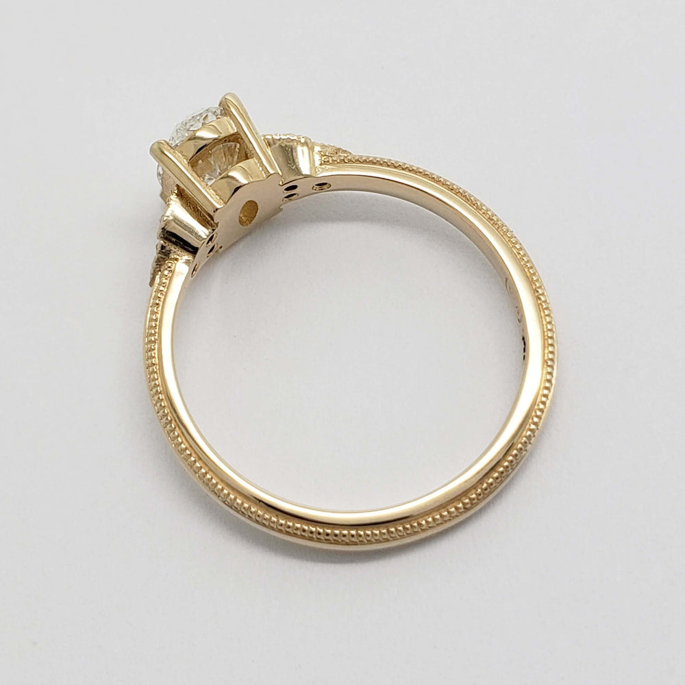 Side view of 14kt yellow gold engagement ring showing millgrain and setting details