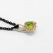 Side view of 14kt yellow gold filigree pendant with round green peridot