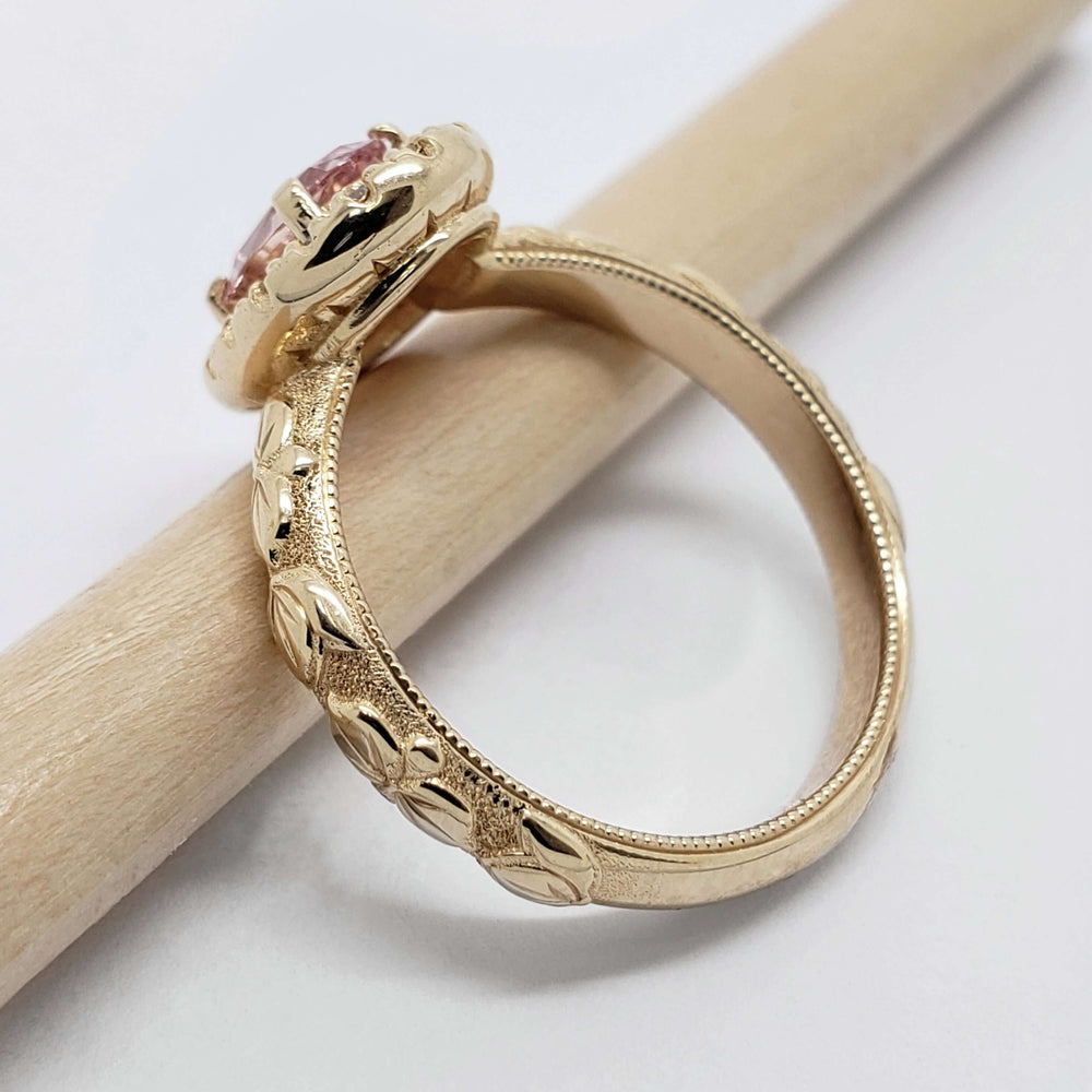 Side view of engraved 14kt yellow gold ring band with millgrain and floral pattern, diamond halo setting