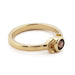 Side view of 14kt yellow gold ring with bezel-set purple Montana sapphire and leaf accents
