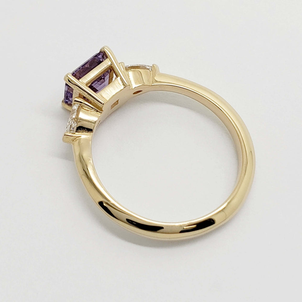 Side profile of yellow gold ring with lavender sapphire center and lab diamond accents