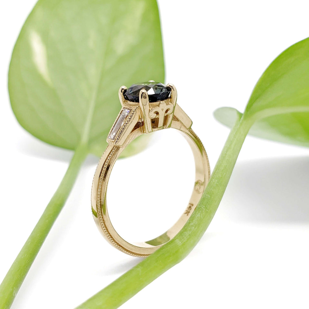 Side view of 14K yellow gold Montana sapphire ring with baguette diamonds and leaf background