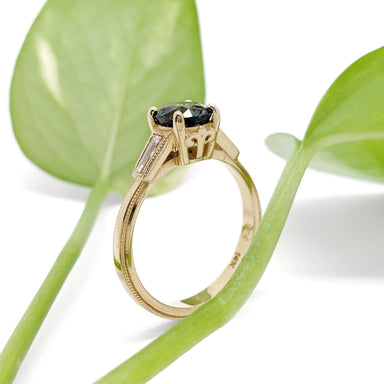 Side view of 14K yellow gold Montana sapphire ring with baguette diamonds and leaf background