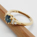 Side view of 14k yellow gold ring with blue Montana sapphire and diamonds on a pencil