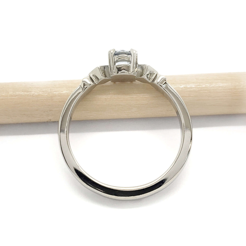 Side profile of 14kt white gold Montana sapphire engagement ring beside a pencil