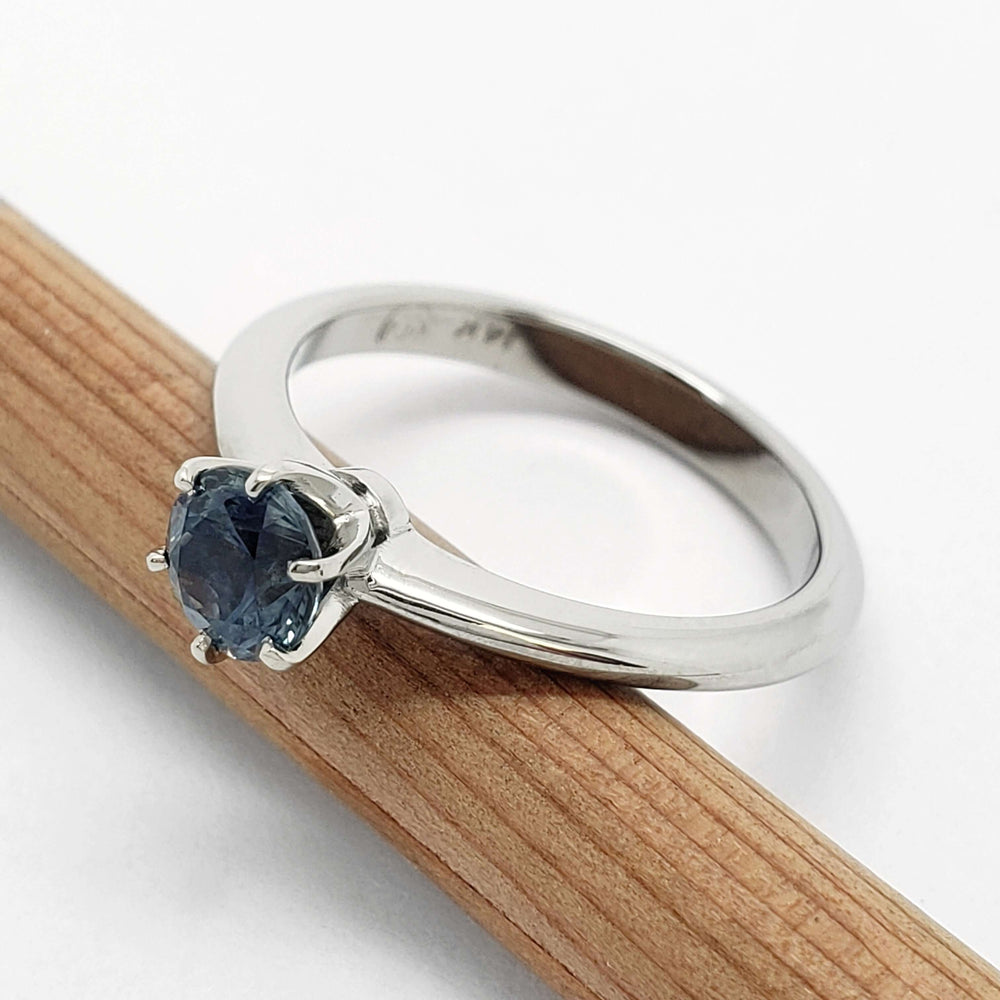 Side view of 14kt white gold Montana sapphire solitaire ring on a wooden pencil