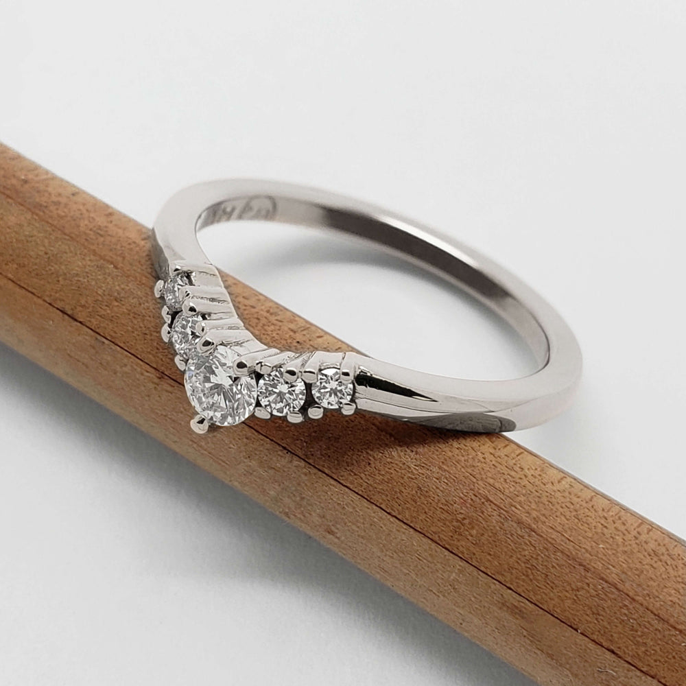 Side angle of 14kt white gold chevron diamond wedding ring on a pencil