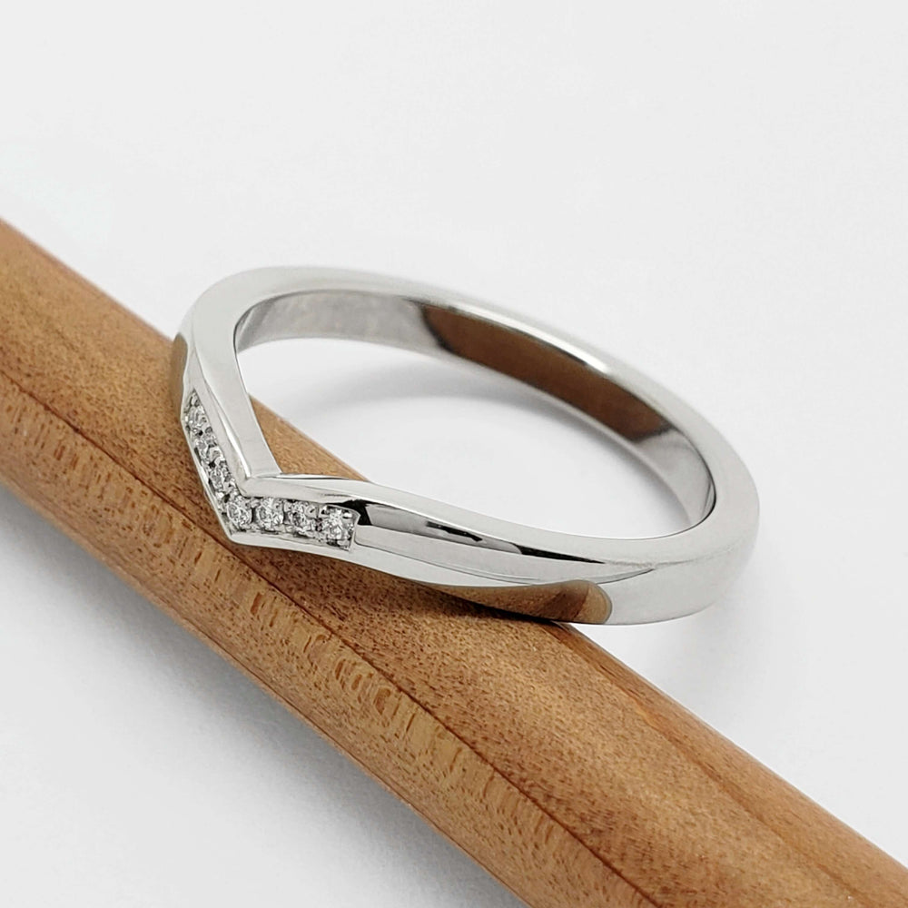 Side view of 14kt white gold chevron wedding ring with pavé diamonds on pencil