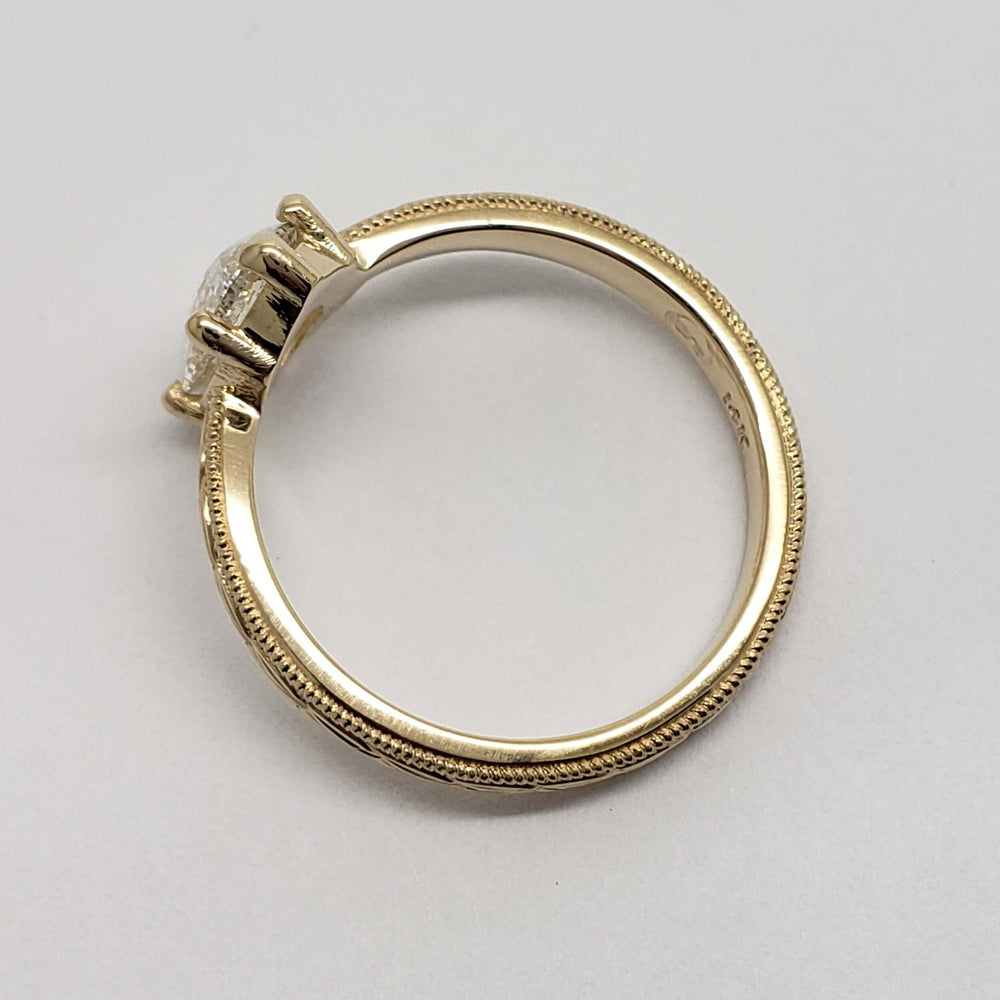 Side view of engraved 14kt yellow gold band with pear lab diamond setting
