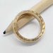 Side view of engraved 14kt yellow gold wedding ring with millgrain and bead details, on pencil