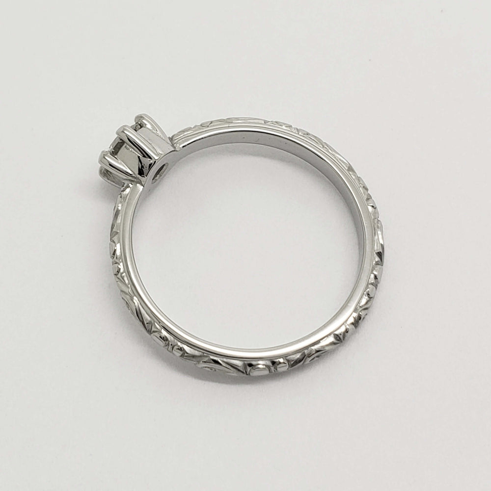 Side view of engraved white gold ring band and diamond setting