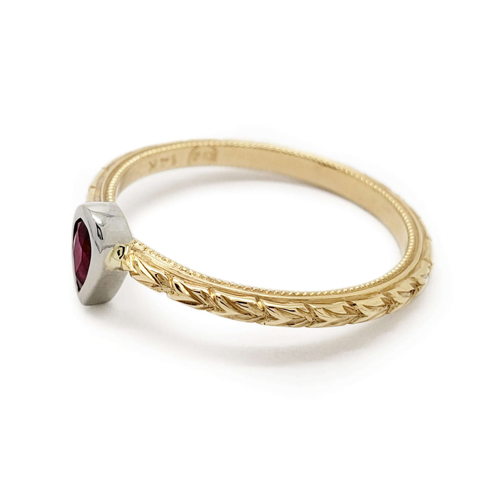 Side view of engraved yellow gold ring with pear ruby bezel set in white gold