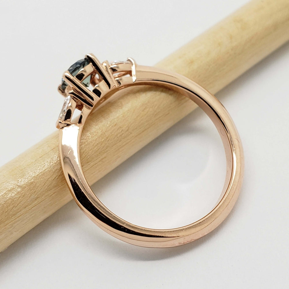 Side view of 14kt rose gold Montana sapphire and lab diamond ring on a pencil