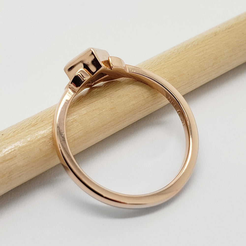 Side view of 14kt rose gold ring with bezel-set green sapphire and leaf details
