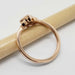 Side view of 14kt rose gold ring with bezel-set green sapphire and leaf details
